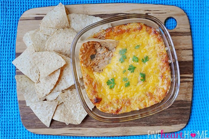 aerial view of Chicken Enchilada Dip with tortilla chips on wooden cutting board