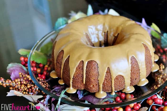 Pumpkin Bundt Cake with Biscoff glaze, on a platter decorated with fall leaves and berries.