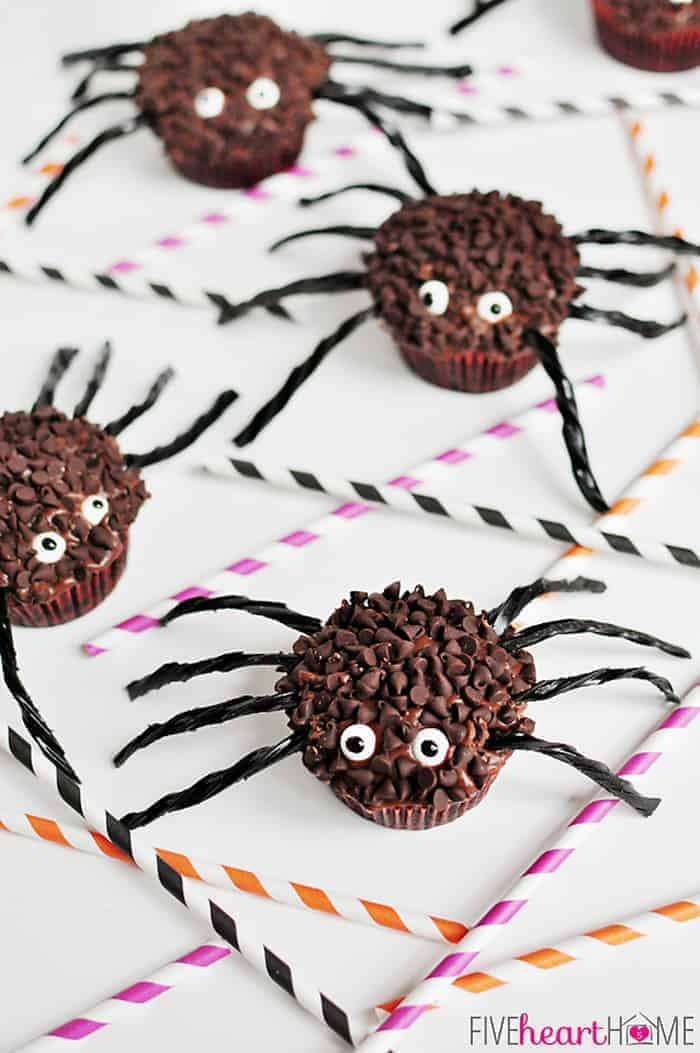 Spider Cupcakes crawling across a white table scattered with striped paper straws