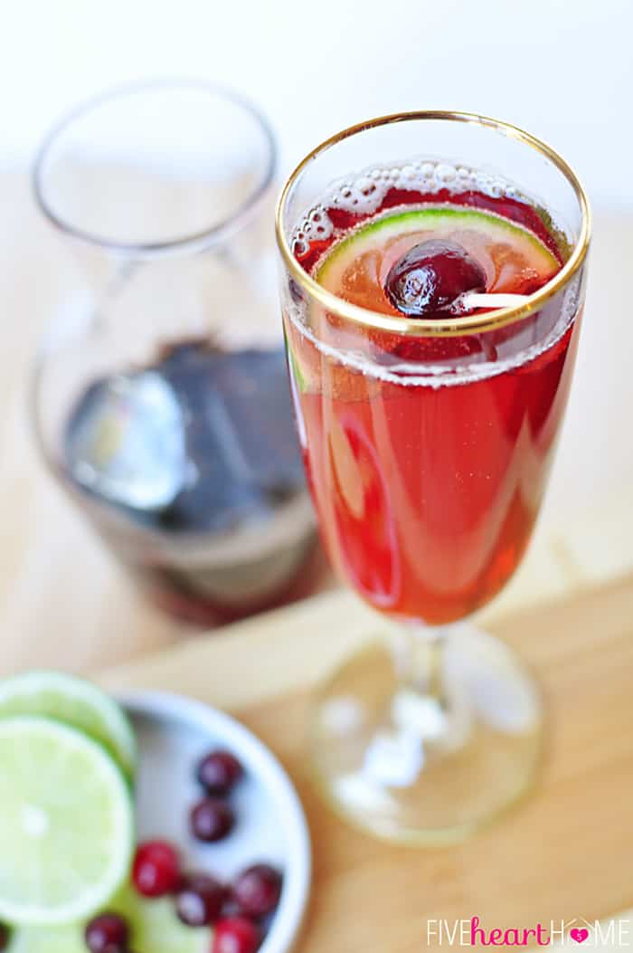 Cranberry Pomegranate Bellinis with Lime ~combine fruity simple syrup with champagne (or seltzer) and a squeeze of lime for a sparkling drink that's perfect for celebrating the holidays or ringing in the New Year! | FiveHeartHome.com via @fivehearthome