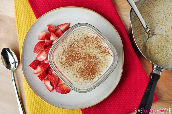 Aerial view of pot of Quinoa Pudding with some dished up in a bowl, with a side of chopped strawberries