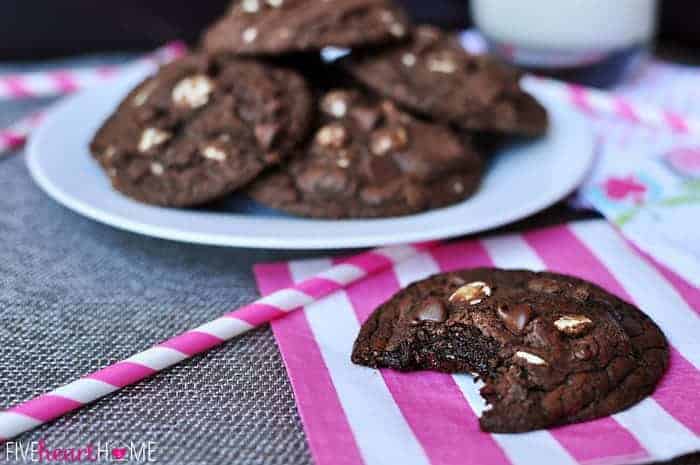 Triple Chocolate Fudge Cookies ~ intense chocolate flavor with chewy, gooey centers and two types of chocolate chips | FiveHeartHome.com Close-up of Fudge Cookie with a plate of cookies in the background