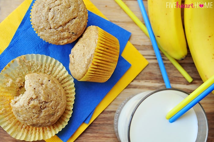 Healthy Banana Muffins ~ these muffins are delicious and wholesome, boasting healthy ingredients including whole wheat flour, coconut oil, yogurt, and honey! | FiveHeartHome.com Aerial view of Healthy Banana Muffins with bananas and glass of milk on table.