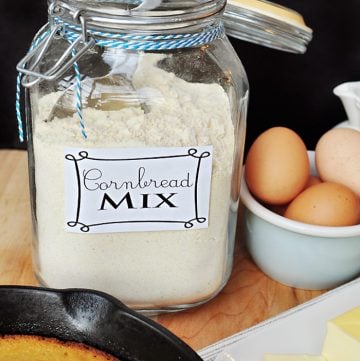 Glass jar of Homemade Cornbread Mix with ingredients for making a pan of cornbread on the table
