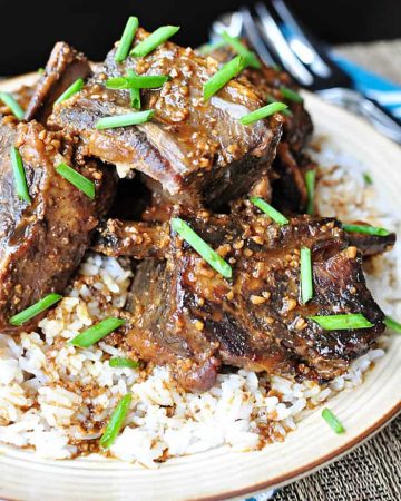 Asian Short Ribs served over rice on a plate.