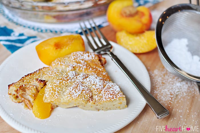 Serving on white plate with powdered sugar and fresh peaches on the side.