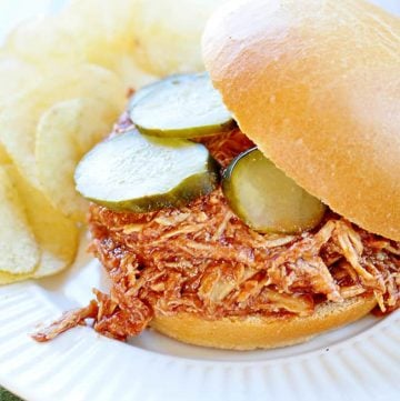 Slow Cooker Chicken Sloppy Joes with pickles on a plate with potato chips.
