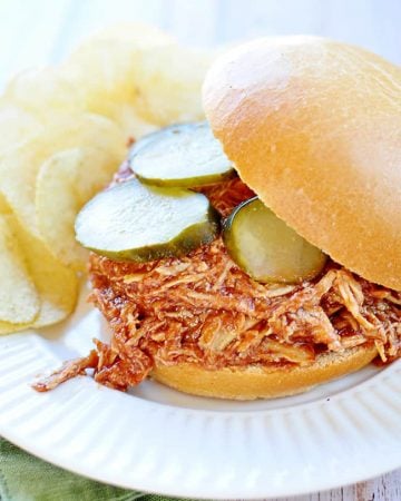 Slow Cooker Chicken Sloppy Joes with pickles on a plate with potato chips.