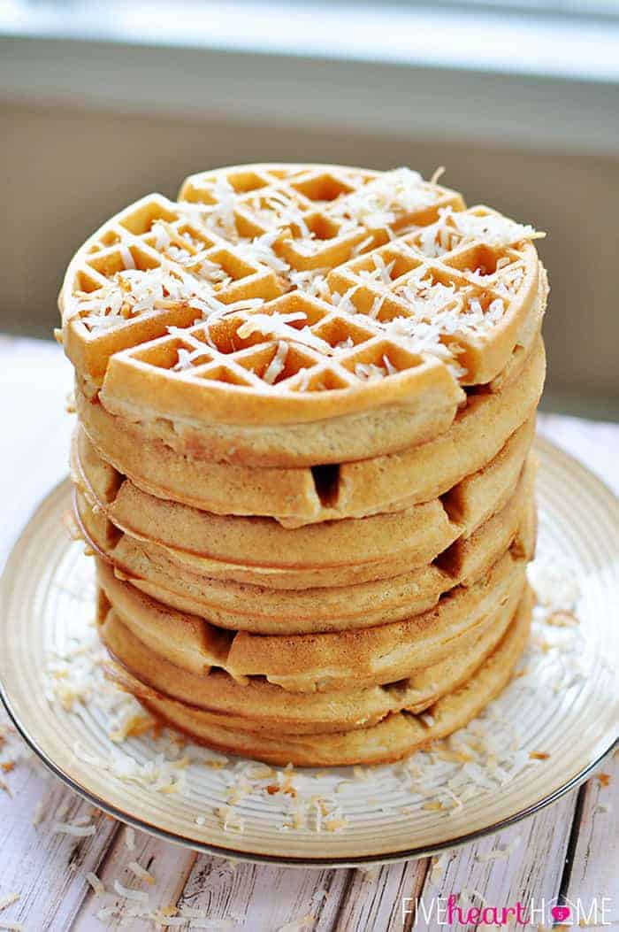 Dairy-Free Coconut Waffles ~ made with whole wheat pastry flour, coconut milk, coconut oil, and honey...tender, golden, and delicious! | FiveHeartHome.com Dairy-Free Coconut Waffles Stacked on a Plate and Topped with Shredded Coconut