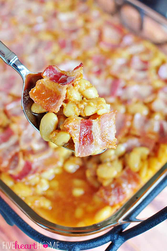 Easy Southern Baked Beans ~ this sweet and savory side dish is topped with bacon, and it's quick to whip up using canned white beans | FiveHeartHome.com Spoonful of Southern Baked Beans out of baking dish.