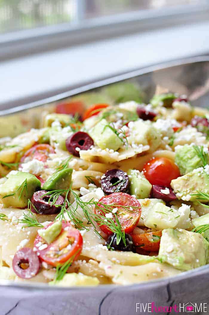 Close-up of ingredients in Tomato Cucumber Pasta Salad with avocado, Kalamata olives, Feta, and fresh dill.