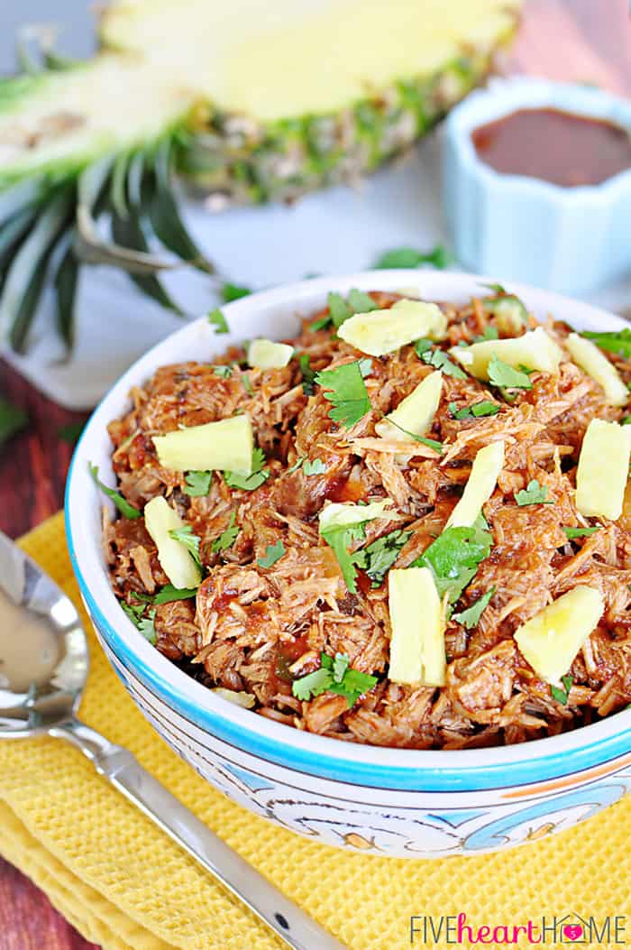 Slow Cooker Pineapple Pulled Pork with Pineapple BBQ Sauce in a Decorative Bowl Atop a Yellow Placemat 