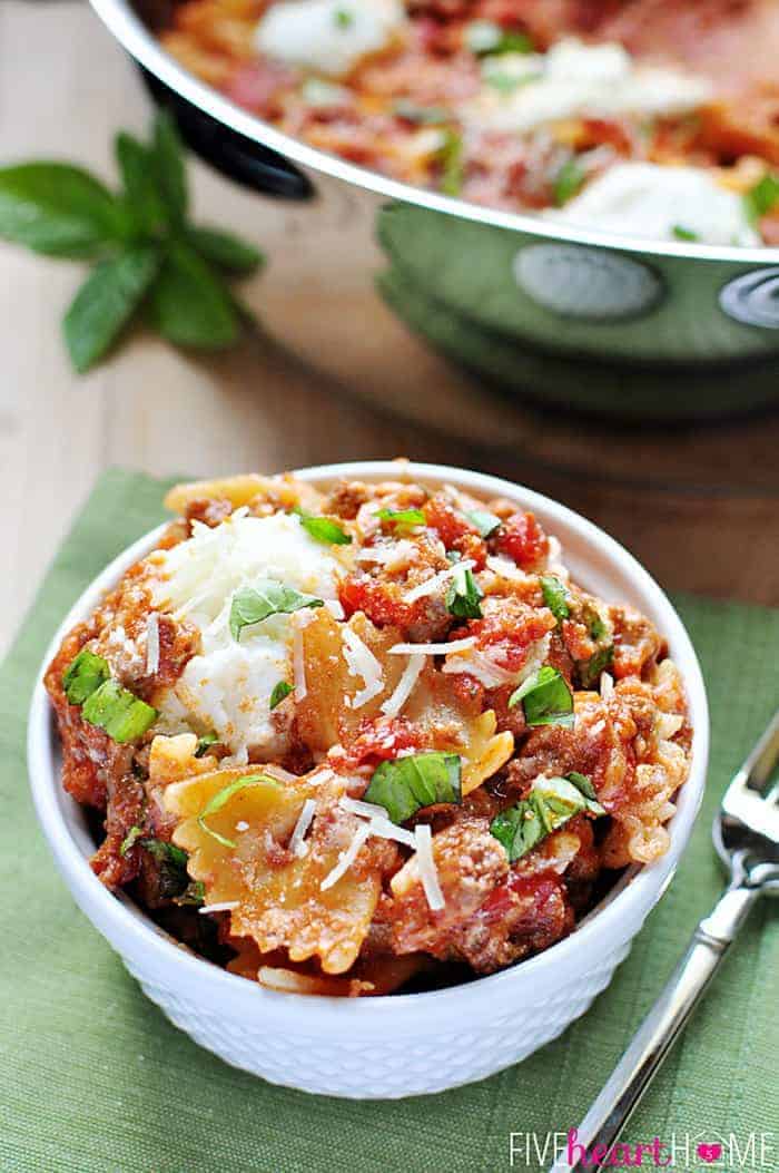 Served in a white bowl and garnished with basil and parmesan.