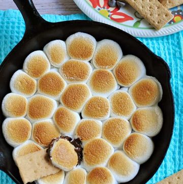 Aerial view of S'mores Dip in skillet with graham crackers on plate.