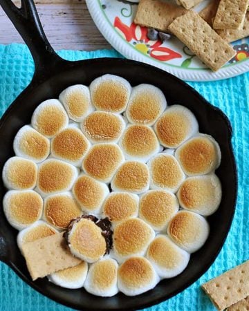 Aerial view of S'mores Dip in skillet with graham crackers on plate.