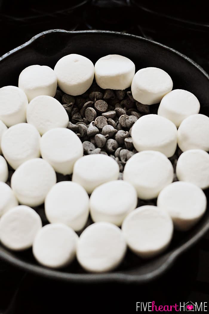 S'mores Dip ~ melted chocolate and toasty marshmallows bake up in a skillet; scoop up with graham crackers for a perfect party dessert! | FiveHeartHome.com Chocolate chips and marshmallows in skillet.