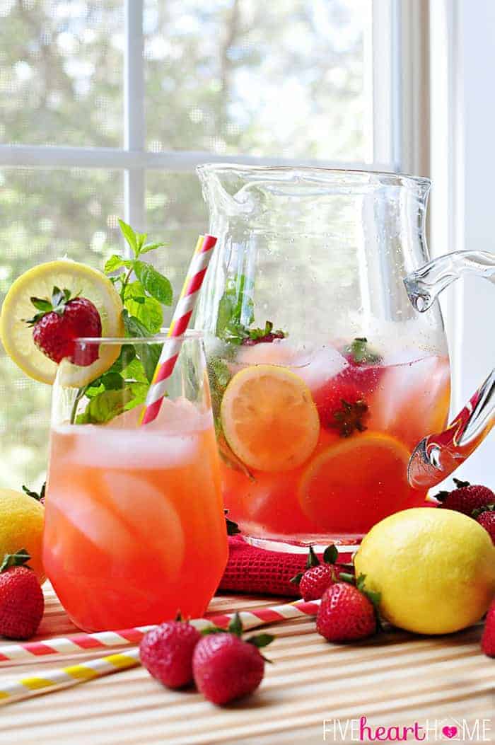 Strawberry Lemonade Mojitos {or} Faux-jitos in a Glass with Garnish of Strawberries, Lemon Slice and Mint Garnish and a Large Glass Pitcher