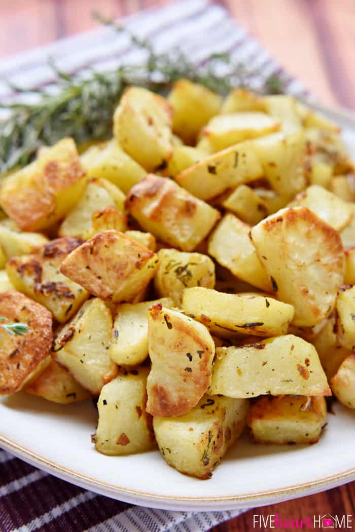 Garlic and Herb Roasted Potatoes ~ a simple, delicious side dish flavored with fresh rosemary and thyme | FiveHeartHome.com Piled Hight on a White Platter with Fresh Garnishes of Rosemary and Thyme