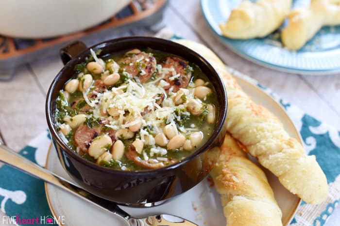 Bowl garnished with parmesan and breadsticks on side.