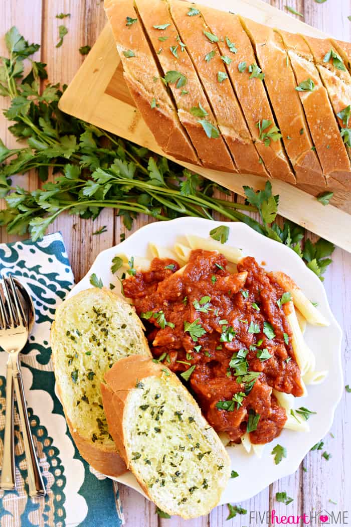 Aerial View of Garlic Bread with Fresh Garlic and Parsley on a White Plate with Pasta and Marinara Sauce 