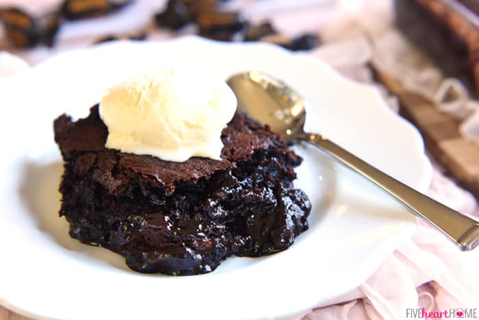 Warm Chocolate Cobbler ~ features moist chocolate cake floating on top of a caramel-streaked, coffee-laced, molten chocolate sauce! | FiveHeartHome.com Warm Chocolate Cobbler with a Scoop of Ice Cream on a White Scalloped Plate