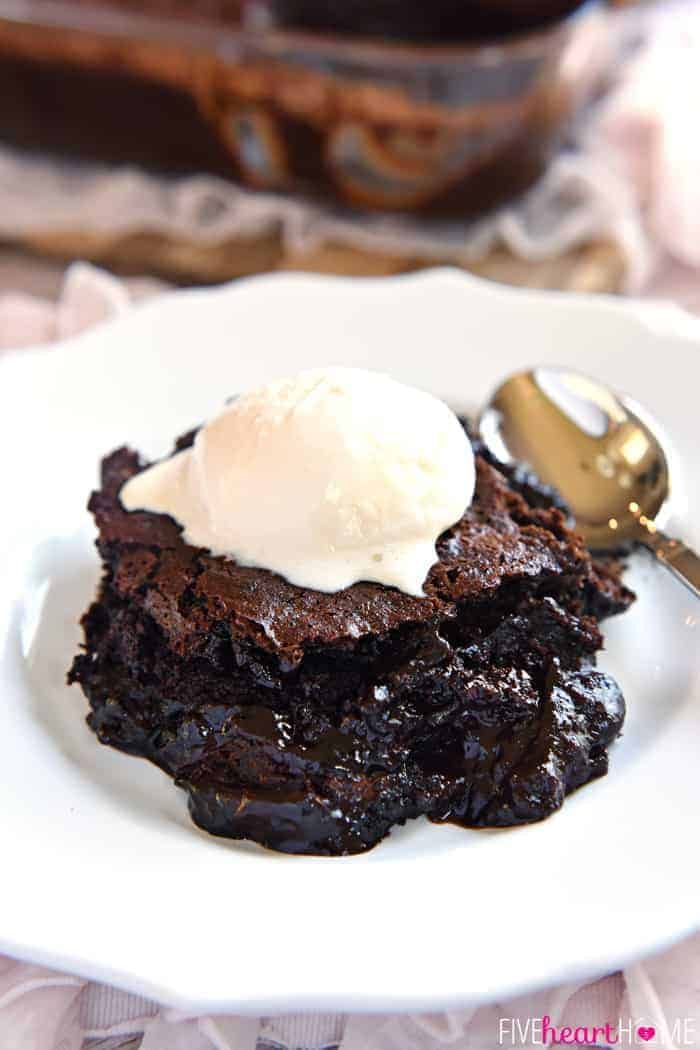 Chocolate Cobbler on a white plate with a spoon topped with melting vanilla ice cream