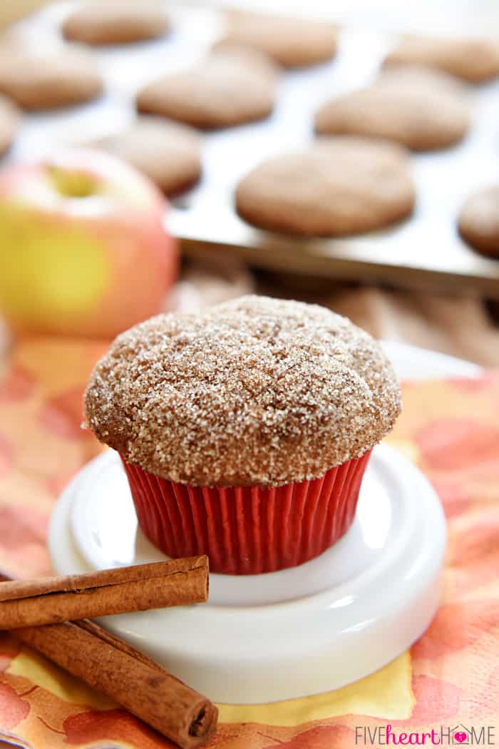 Whole Wheat Apple Cinnamon Muffins are soft and moist, bursting with tender apples, made wholesome by whole wheat flour and coconut oil, and topped with a cinnamon sugar coating | FiveHeartHome.com Muffin topped with cinnamon sugar in red paper liner