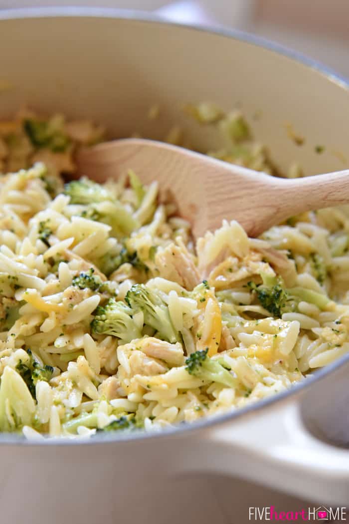 Wooden Spoon Scooping Out Orzo from White Enamel Cast Iron 