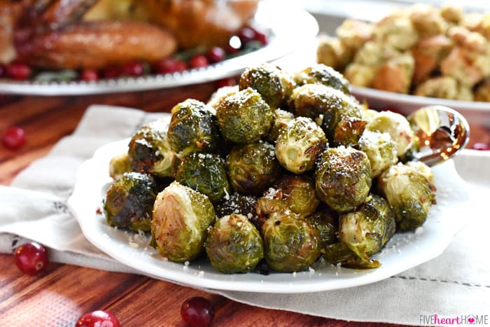 Roasted Brussels Sprouts with Parmesan on White Platter with Silver Serving Spoon