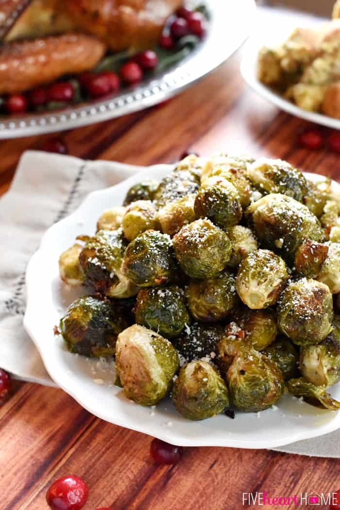 Roasted Brussels Sprouts with Parmesan White Scalloped Platter with Turkey in the Background 