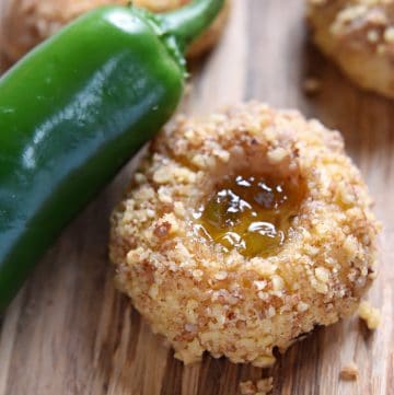 Close-up of Cheddar Jalapeño Jelly Thumbprint Cookies with fresh jalapeño on side.