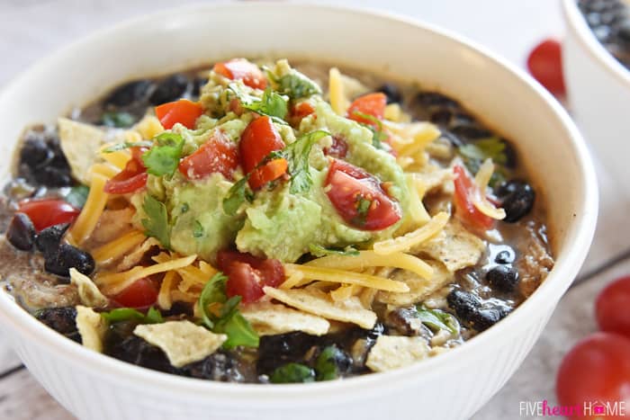 Bowl garnished with tortilla chips, cheese, gucamole, and tomatoes