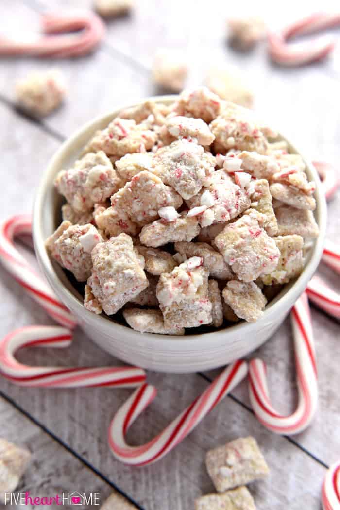 Christmas Puppy Chow in a bowl garnished with crushed candy canes.