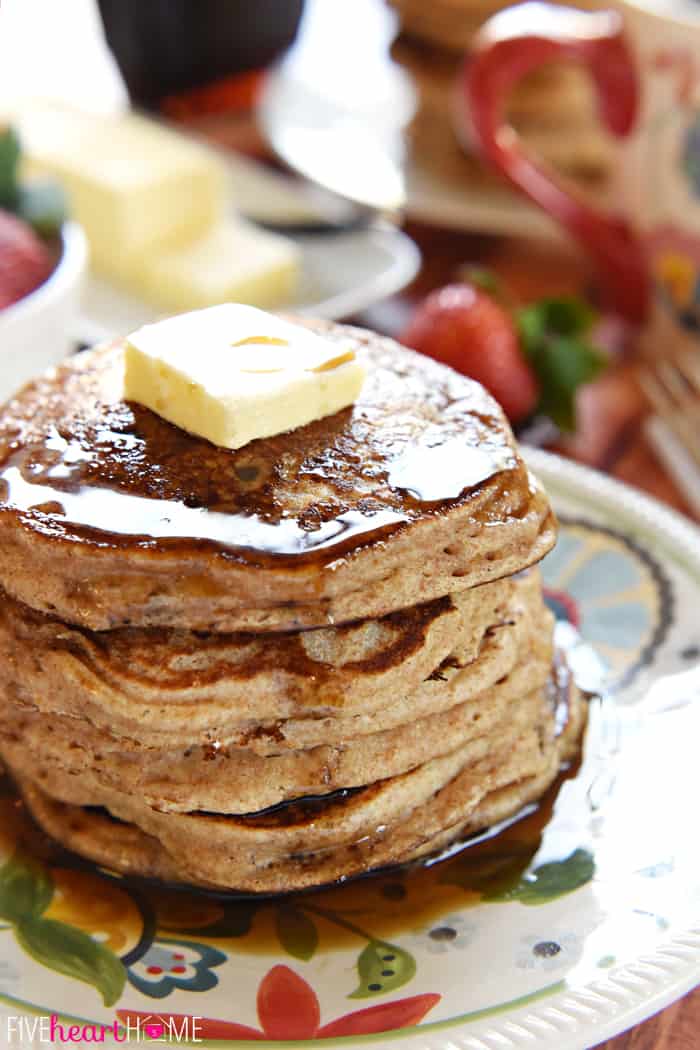 Close-Up of a stack of whole wheat pancakes, topped with a pat of butter and syrup.