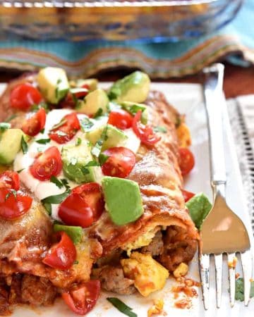 Breakfast Enchiladas ~ stuffed with sausage, eggs, and cheese, then topped with homemade red enchilada sauce, more cheese, and all of your favorite enchilada garnishes, these are even better than breakfast tacos! | FiveHeartHome.com