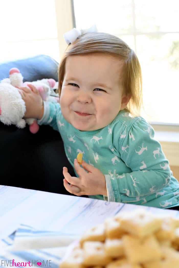 Toddler smiling while eating Cheese Crackers.