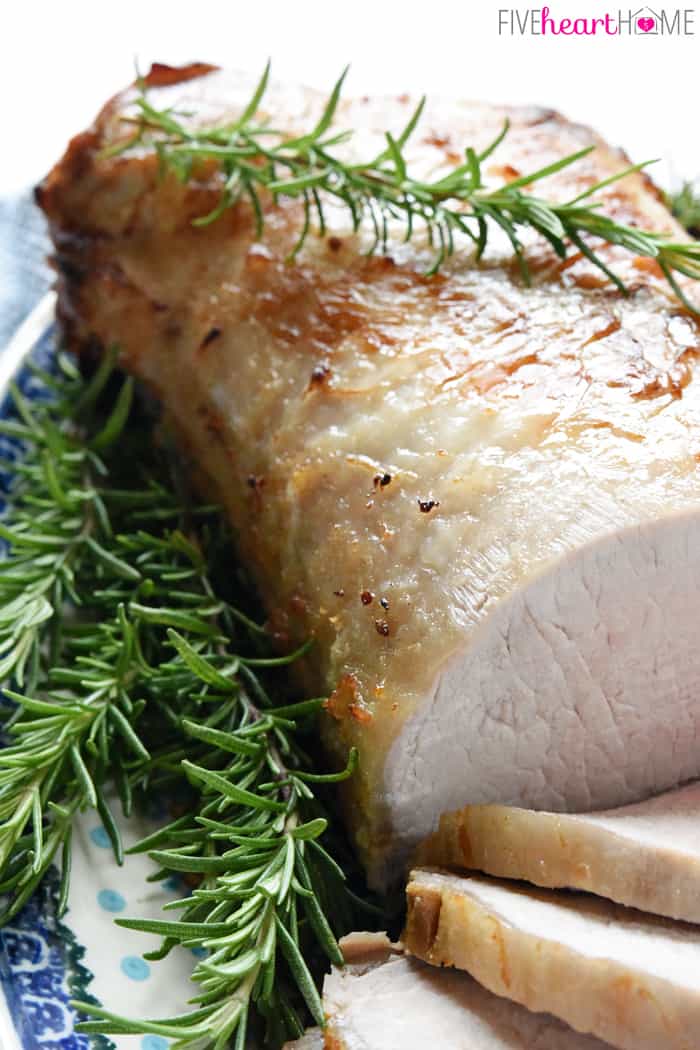 Close-up of brined pork loin on platter with rosemary.