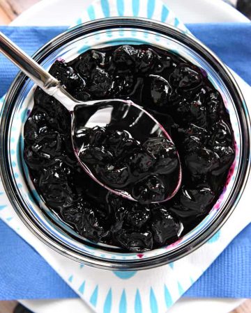 Aerial view of Blueberry Compote in glass bowl with spoon.