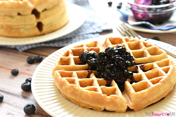 Homemade Whole Wheat Waffle Mix ~ an economical pantry staple for conveniently whipping up fluffy, all-natural, 100% whole wheat waffles! | FiveHeartHome.com Topped with blueberry compote on a white plate.