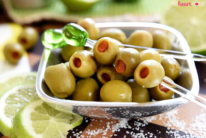 Pewter bowl of pimento-stuffed olives, some on picks.