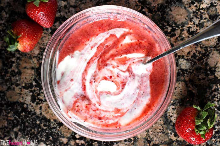 Aerial view of fruit puree being stirred into yogurt.