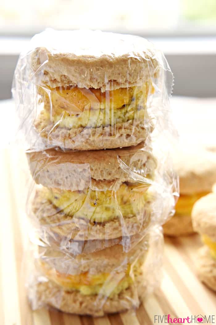 Easy Freezer Breakfast Sandwiches ~ cheesy scrambled eggs with ham are sandwiched inside of flaky biscuits in these make-ahead sandwiches that freeze beautifully...perfect for busy mornings and breakfast on-the-go! | FiveHeartHome.com Stack of Freezer Breakfast Sandwiches, wrapped in plastic wrap and ready for the freezer.