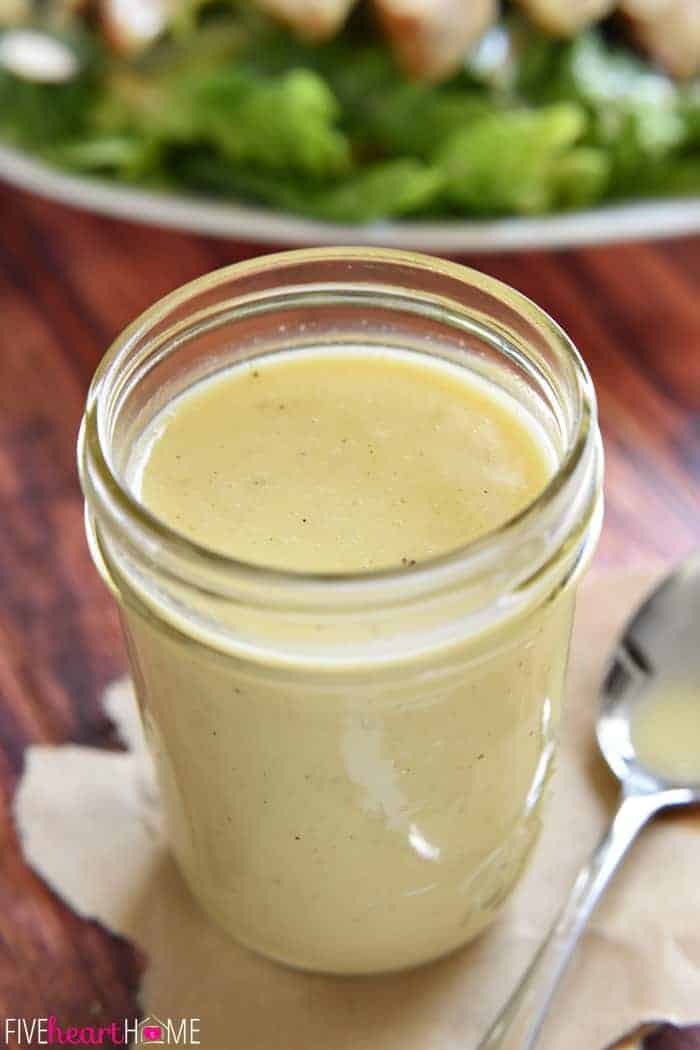 Honey Mustard Dressing in mason jar with salad in the background.