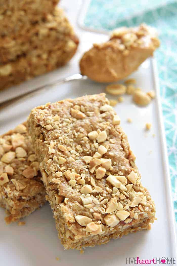 Peanut Butter Oatmeal Bars ~ loaded with wholesome oatmeal and whole wheat flour, flavored with peanut butter, and sweetened with honey, these soft-baked oatmeal bars make a yummy, on-the-go breakfast or snack! | FiveHeartHome.com Peanut Butter Oatmeal Bars stacked on a white platter with a spoonful of peanut butter in background.