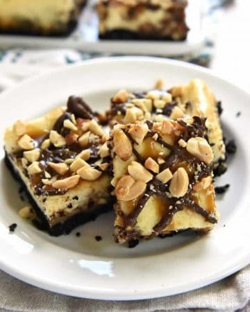 Snickers Cheesecake Bars ~ a crunchy Oreo crust is topped with a decadent layer of Snickers-studded cheesecake, drizzled with smooth chocolate and gooey caramel, and then sprinkled with salty chopped peanuts! | FiveHeartHome.com