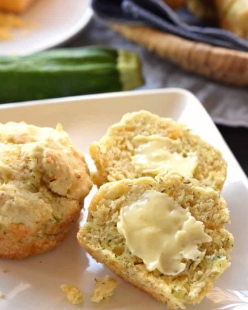 Savory Zucchini Muffins sliced open and spread with butter.