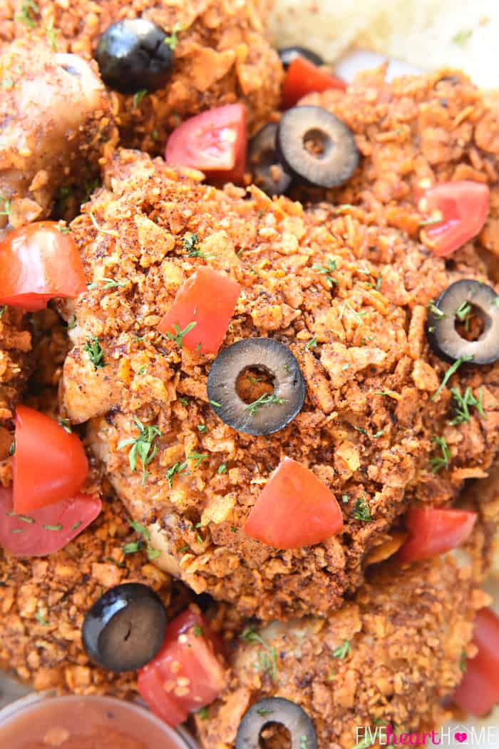 Taco Baked Chicken ~ tender and juicy on the inside with a crunchy coating of taco-seasoned tortilla chips, this Tex-Mex twist on baked chicken is a simple and delicious dinner for any night of the week! | FiveHeartHome.com Baked Chicken with Taco Seasoning Garnished with Olives, Tomatoes and Cilantro