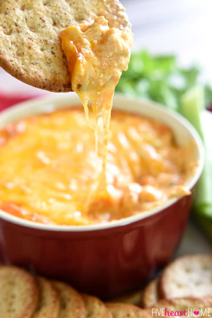 Chicken Wing Dip recipe on cracker with bowl of Buffalo Chicken Dip in background.