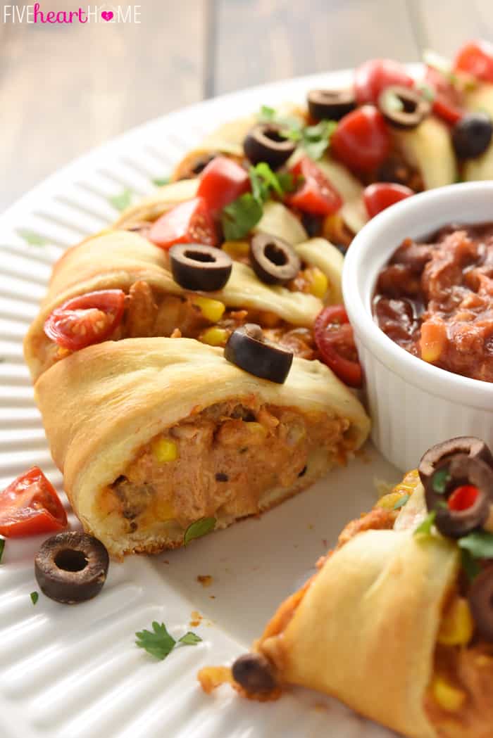 Chicken or Turkey Taco Crescent Ring ~ a delicious way to use up leftover chicken or holiday turkey...mixed with black beans, corn, and cream cheese, flavored with taco seasoning, and wrapped in light, flaky crescent roll dough for an easy yet impressive appetizer or dinner! | FiveHeartHome.com Chicken or Turkey Taco Crescent Ring with Serving Removed and Garnish of Olives, Tomatoes and Cilantro