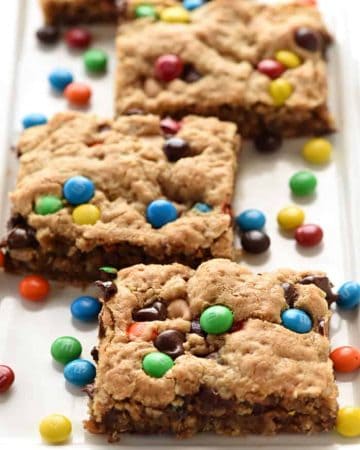 {One-Bowl, Big-Batch} Monster Cookie Bars ~ loaded with chewy oats, decadent peanut butter, colorful M&Ms, chocolate chips, and peanut butter chips, this effortless recipe whips up in no time! It is then spread in a large rimmed sheet pan to yield a big batch of bar cookies, perfect for sharing or serving at parties. Even better, you can customize these yummy bar cookies for various holidays by using seasonal M&Ms! | FiveHeartHome.com